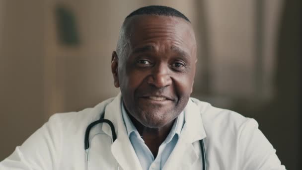シニア男性医師アフリカの男性医療従事者は Webチャットレコードでオンラインで患者をカメラコンサルティングするために遠くのビデオ通話中年の大人の医師の話をします医療ウェブカメラのビュー — ストック動画