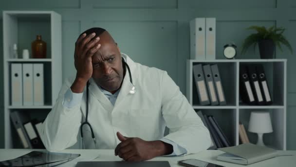 忧心忡忡的非洲裔医生老年男子感到绝望压力疲倦的男子坐在医院认为健康问题压抑了职业倦怠情绪 — 图库视频影像