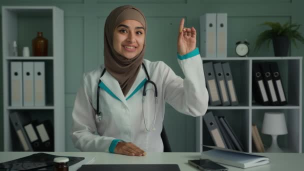 ウェブカメラビューアラビア語の女性のヒジャーブ若い一般開業医遠隔ビデオ通話を話す女性医師使用コンピュータ会議アプリ説明医学ルールは オンラインウイルスパンデミック相談について警告します — ストック動画