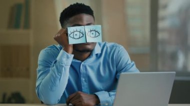 Uykulu tembel ofis çalışanı Afro-Amerikan etnik adam masaya oturur komik komik etiketler yapıştırır yorgun yorgun çalışanlar uyur uyur dinlenir
