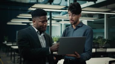 Bilgisayar şirketleri ile çalışan erkek iş adamları dijital iş geliştirme sunumu geliştiriyorlar. İki çok ırklı adam, Arap ve Afrikalı adam ofiste proje yazılımını tartışıyorlar.