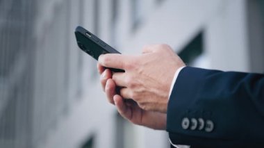 Close-up male hands typing on mobile phone caucasian businessman stand outdoors send text message on social network young man surf internet using smartphone browse email make order in online store
