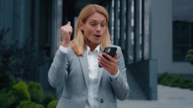 Telefondan iyi haberler okuyan memnun kadın müşteri akıllı telefondan e-posta bildirimi alıyor. Neşeli iş kadını, zaferin tadını çıkarıyor. Dans yarışmasının başarısını kutluyor.