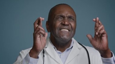 Stüdyoda olgun bir adam var. Gri arka planda. Umut verici doktor cerrahı şans diliyor.