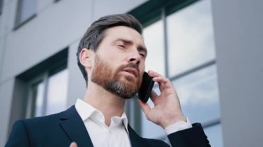 Close-up focused man talking on mobile phone outdoors businessman answering business call using smartphone manager consultant remotely advise client on cellphone communicate with customer calling taxi
