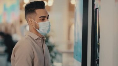Side view businessman man in medical face mask use bank ATM terminal electronic machine touch screen panel for receiving and dispensing money pays problems error currency exchange cash failure mistake