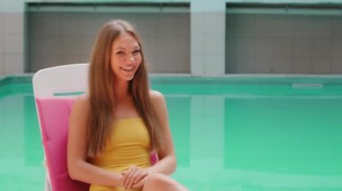 Blonde happy girl young student woman satisfied client tourist model in swimsuit excited looking at camera feel shock positive surprise pointing finger aside promoting summer holiday by swimming pool