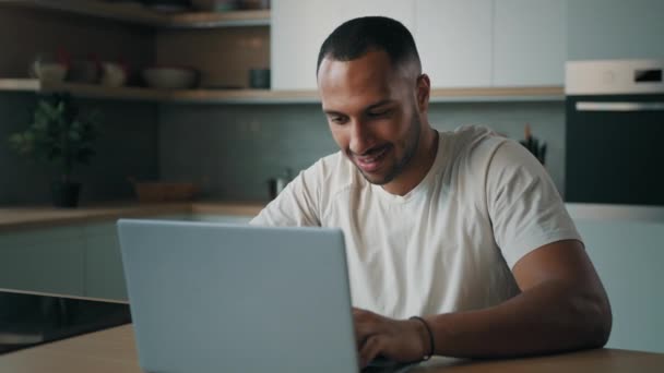 非洲自由职业男美国男人坐在家里厨房打字用笔记本电脑远程聊天用电脑预订订餐网上送餐运动健美营养 — 图库视频影像