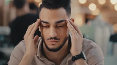 Indian Hispanic ethnic man suffer with headache sad depressed guy businessman has business problem frustrated with pain massage head dizzy unhappy male feel migraine anxiety stress trouble sickness