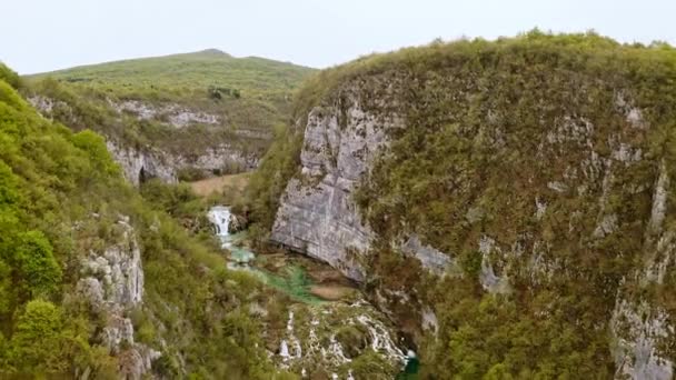 上空から撮影されたクロアチアの緑の森に覆われた空中ドローンビューの山々プリトヴィツェ湖の滝国立公園岩の上の飛行 ヨーロッパの野生自然への観光地 — ストック動画