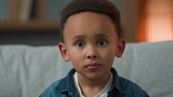 ポートレート悲しいかわいいアフリカ系アメリカ人多人種多民族の子供孤児小さな男の子の生徒の赤ちゃんの深刻な7歳の子供カメラを見て動揺顔の表情孤独差別 — ストック動画