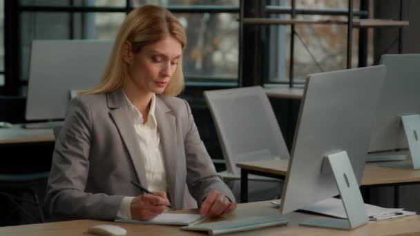 白种人中年成年女性成熟的商业女性女企业家在办公室里用笔记本写笔记打字计算机工作会计写任务构想 — 图库视频影像