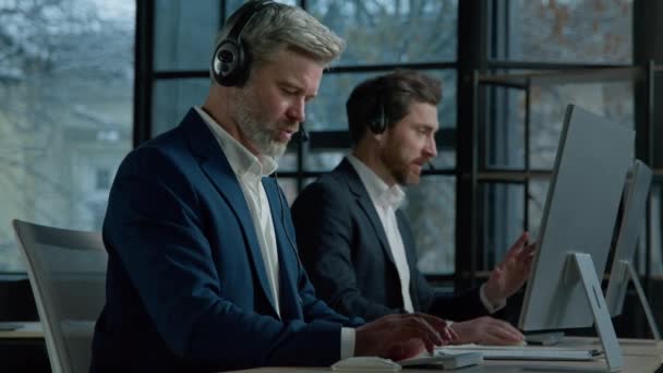 两名男子呼叫中心服务操作员使用耳机与客户进行办公室交谈 集中销售代理销售在线接听来电 为客户提供专业支持 — 图库视频影像