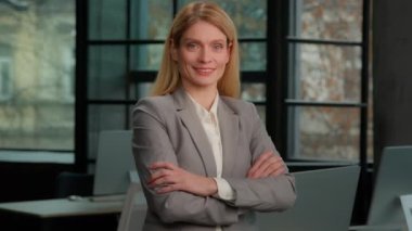 Caucasian millennial 30s mature 40s middle-aged successful confident businesswoman feminism worker CEO lady boss female leader woman posing crossing arms looking at camera in corporate office smiling