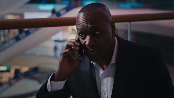 アフリカ系アメリカ人フラストレーションのあるビジネスマンとスマートフォンで話す屋内ストレスのある中年男性のビジネス上の問題 — ストック動画