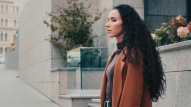 Serious Hispanic Caucasian girl stylish model lady woman waiting meeting on street turning around looking at camera. Confident businesswoman brunette female tourist turn over shoulder in city outdoors