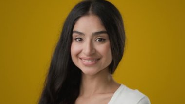 Close up portrait in yellow studio copy space for advertising Indian smiling 20s woman mock up isolated girl lady female with perfect make-up skin hair smile dental healthy white teeth toothy headshot