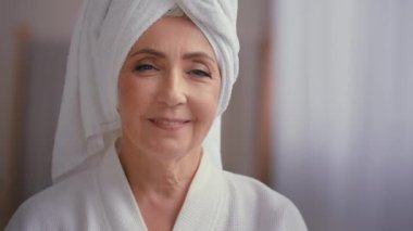 50 'li yaşlarda, kafasında havluyla banyoda kadın portresi yakın. Kameraya dön ve 60' lı yaşlarda banyo yapmış olgun bir kadın gülümse. Yüzünde estetik estetik cerrahi ile mutlu bir gülümseme.