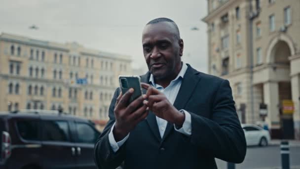 非洲中年企业家商人在城市街道上与手机举行视频电话会议 与智能手机聊天 在户外虚拟交谈 与律师交谈 讲网络摄像头 — 图库视频影像