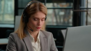 Caucasian middle-aged adult woman business female 30s businesswoman worker in office with headset using computer talking working customer support service operator helpline agent manager in headphones