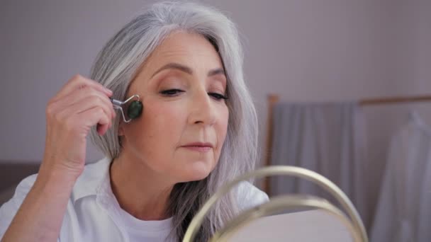 근육질의 거울을 할머니는 얼굴에 마세어를바르고 있으며 피부에는 마사지를 — 비디오