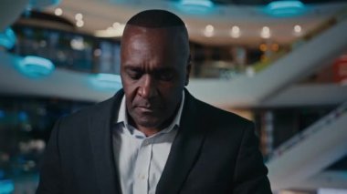 Pensive senior ethnic businessman thinking answer displeased mobile call African American angry businessman talking mobile phone indoors stressed middle-aged male man conflict problem talk furious