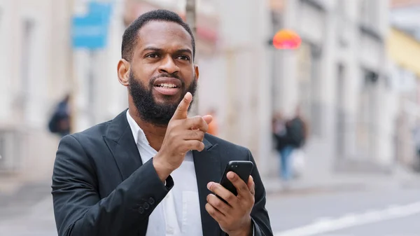 アフリカ系アメリカ人の髭を生やした男が携帯電話の画面を見てスマートフォンを持っている 民族男性の専門家のビジネスマンの方向道路を検索 — ストック写真