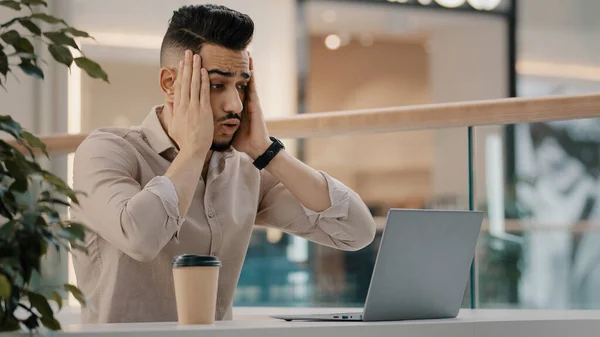 Sad shocked stressed Hispanic Indian man worker manager freelancer entrepreneur manager in cafe has problem with laptop app reading bad news worried with email shock stress business failure lost job