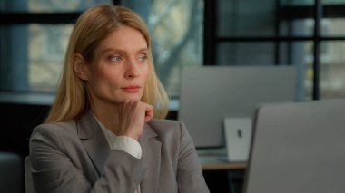 Thoughtful concerned Caucasian middle-aged adult 40s woman working on laptop computer in office looking away thinking solving problem. Serious pensive businesswoman search inspiration make decision