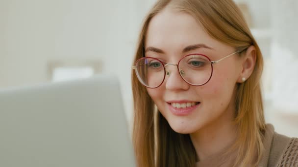 メガネの目に白人女性の顔の女の子を閉じるノートパソコンの画面を見てください コンピュータ仕事で忙しいフリーランスの笑顔ビジョンレーザー矯正手術の概念を勉強 — ストック動画