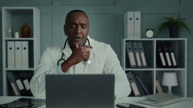 Male medical worker african man doctor general practitioner participate online webcam conference on laptop use technology app give consultation in video chat consulting patient about covid-19 pandemic