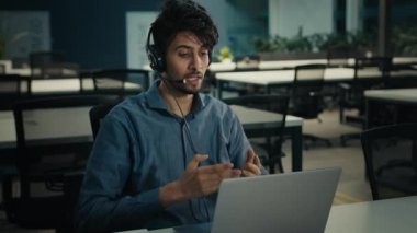 Indian man internet teacher lawyer expert businessman in headphones sit at office talking video conference online call on laptop support client distant hold business documents telemarketing profession