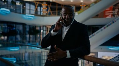 50 'lerin danışmanı, iş arkadaşlarını arıyor. İş ortağı, kapalı bir ofiste akıllı telefonla konuşuyor. Açıklama yapıyor. Afrikalı girişimci iş adamı arıyor. Cevap veren cep telefonu.