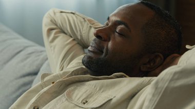 Headshot calm relaxed happy african american man relax resting on couch enjoying calmness sleepy lazy male dreamer dozing on comfortable sofa in living room lies with eyes closed dreaming meditating