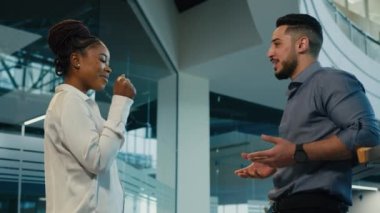 Diverse multiracial friendly business partners colleagues African American woman with Arabian Indian man talking in office hit with fists power five respect friendship partnership support gesture