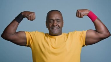 Portrait mature sports african man posing in studio gray background strong muscular athletic male athlete sportsman demonstrates biceps inflated triceps middle aged bodybuilder showing strong muscles