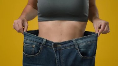 Unrecognizable sport woman in large big size jeans. Close up female strong abdominal tummy slim slender thin body waist girl showing body slimming fitness weight loss dancing happy healthy lifestyle