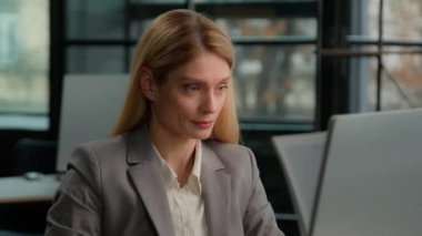 Middle-aged female entrepreneur office worker Caucasian adult woman working with laptop computer celebrate good result win success achievement. Happy businesswoman celebrate online business winning