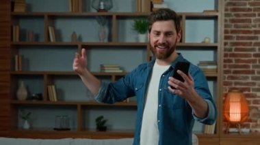 Adult caucasian bearded man blogger make group selfie photo with multiracial friends on mobile phone ethnic diversity people having fun at home smiling posing for smartphone camera union friendship