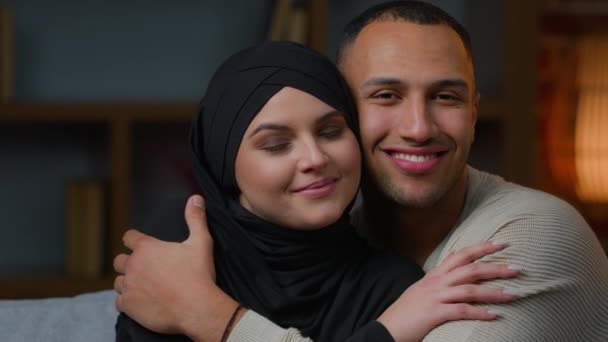 亲密的夫妇房主肖像多种族家庭非洲裔美国男人抱着心爱的阿拉伯穆斯林女人躺在沙发上拥抱年轻的妻子 女朋友和男友放松 — 图库视频影像