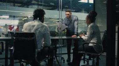 Arabian Indian company CEO project manager male boss leader executive man businessman with contract paper document check report information talking to diverse business team analyze paperwork in office