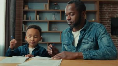 African American father teach little son write help ethnic little schoolboy with writing test lesson class dad with child boy doing homework parent helping kid with studies home learning homeschooling