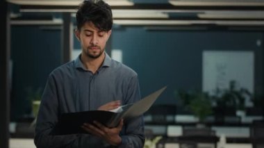 Young indian man analyst office worker manager businessman lawyer check documents folder read financial report business plan commercial contracts male expert concentrated on documentation loan bills