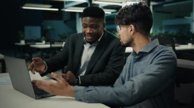 Diverse businessmen african american indian men talking discussing online project on computer sit at office desk two multiracial 30s male colleagues use laptop brainstorming teamwork business briefing