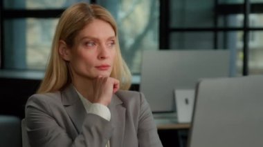 Thoughtful concerned Caucasian middle-aged adult 40s woman working on laptop computer in office looking away thinking solving problem. Serious pensive businesswoman search inspiration make decision