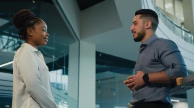 Two multiethnic multiracial colleagues in office talking diverse entrepreneurs African American woman businesswoman and Arabian Indian man businessman talk giving high five partnership unity gesture