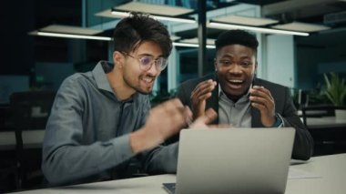 Business success happy winners multiethnic diverse men colleagues work with computer in office African american Indian businessmen win online bet lottery celebrate victory approval project good result