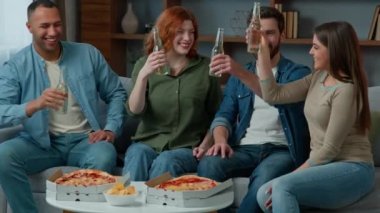 Group of happy multiethnic diverse friends having fun clinking bottled beer at home drinking alcohol at festive table with pizza adults people celebrate together Friday party birthday new year holiday