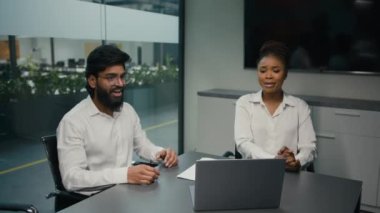 Business partners multiracial diverse company coworkers colleagues in office Indian man and African woman solving online problem with laptop computer win celebrate good news achieve project success