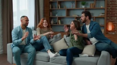 Group of diverse ethnic multiracial friends girls guys sit on sofa at home talking argue conflict friendly dispute debate discussing problem ambitious expressive men women arguing discussion indoors